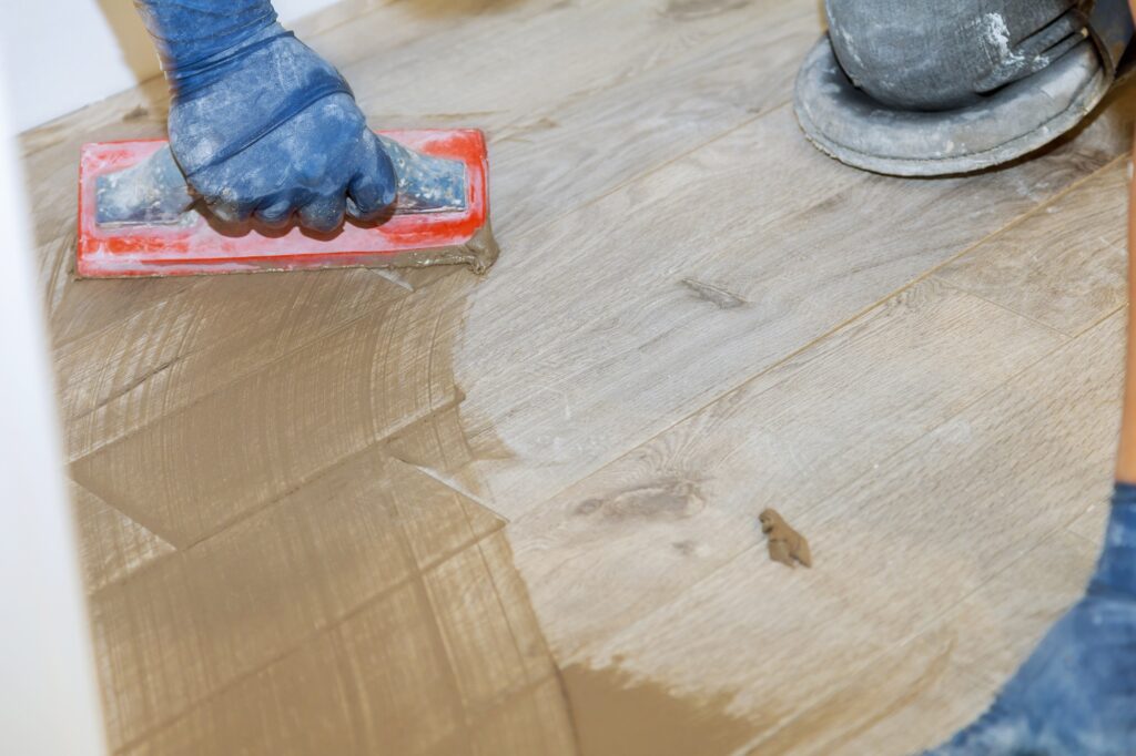 Builder applying grouting on shower tiles in bathroom gray cement mortar